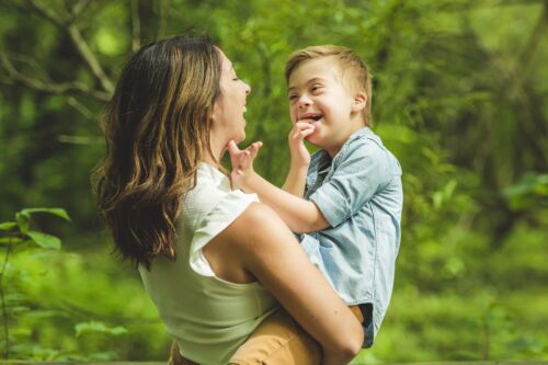 Portrait of a little boy with down syndrome while playing in a park with his mother